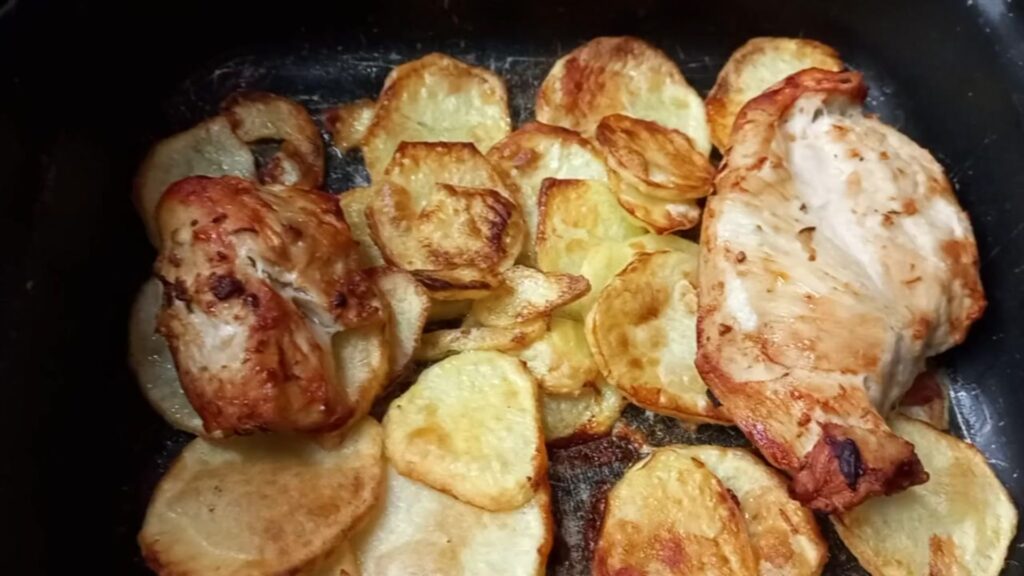 Peito de frango dourado preparado na airfryer acompanhado de batatas em rodelas crocantes, assados sem óleo
