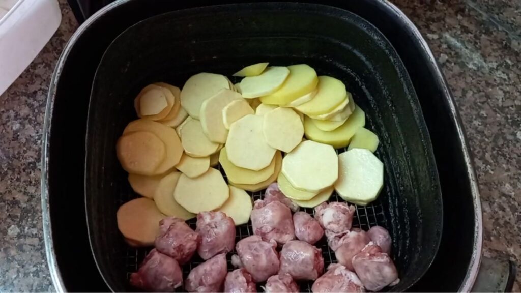 Batata e linguiça cruas dispostas na airfryer antes do preparo