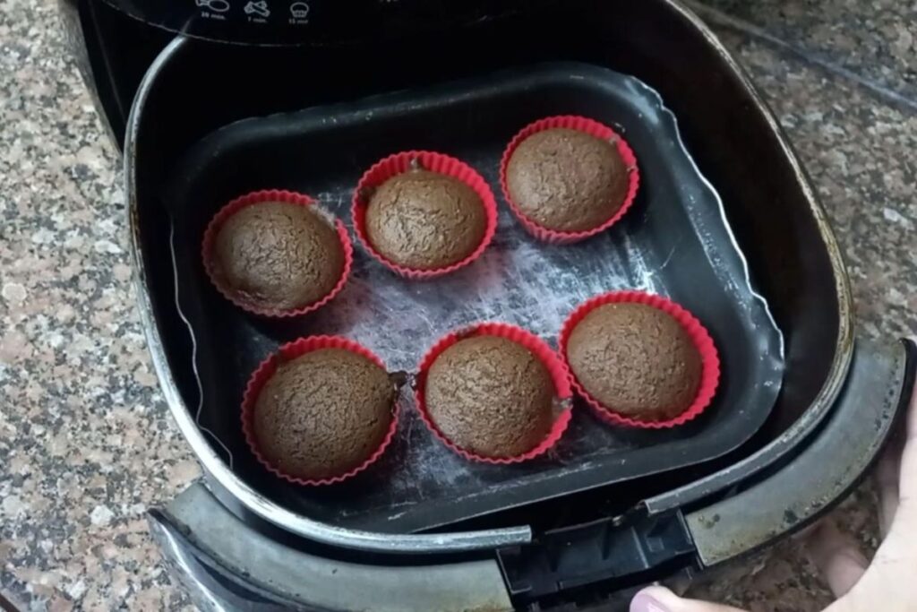 Massa de chocolate sendo colocada em forminhas de silicone coloridas para cupcake