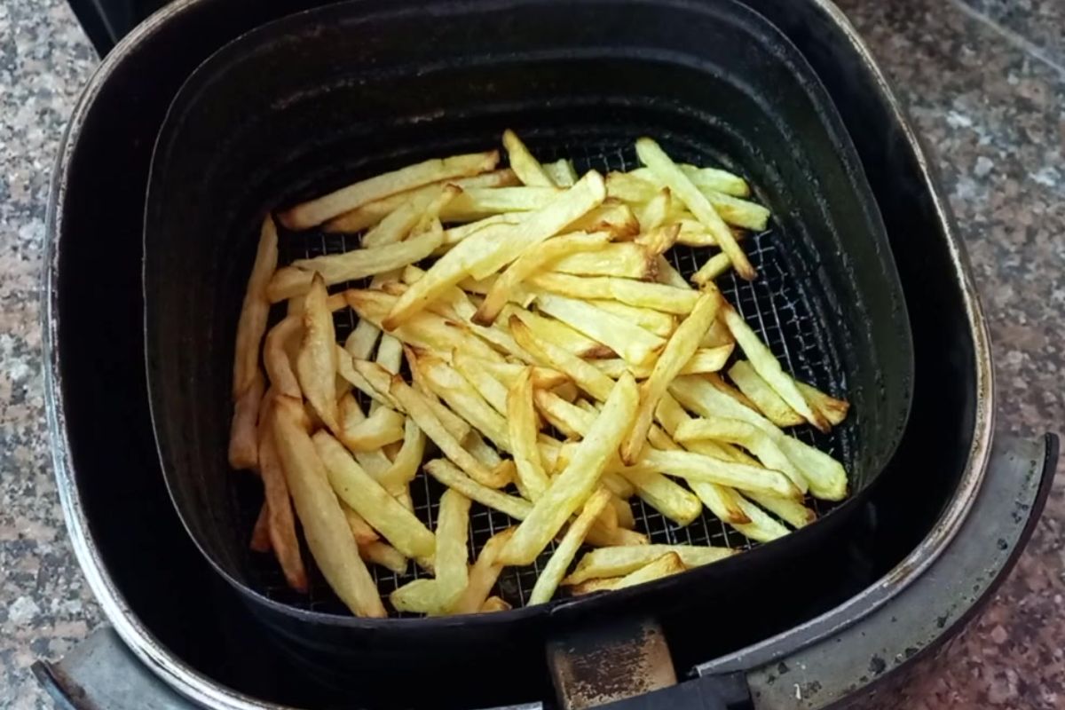 Batata frita na airfryer dourada e crocante, ainda no cesto da fritadeira elétrica após o preparo