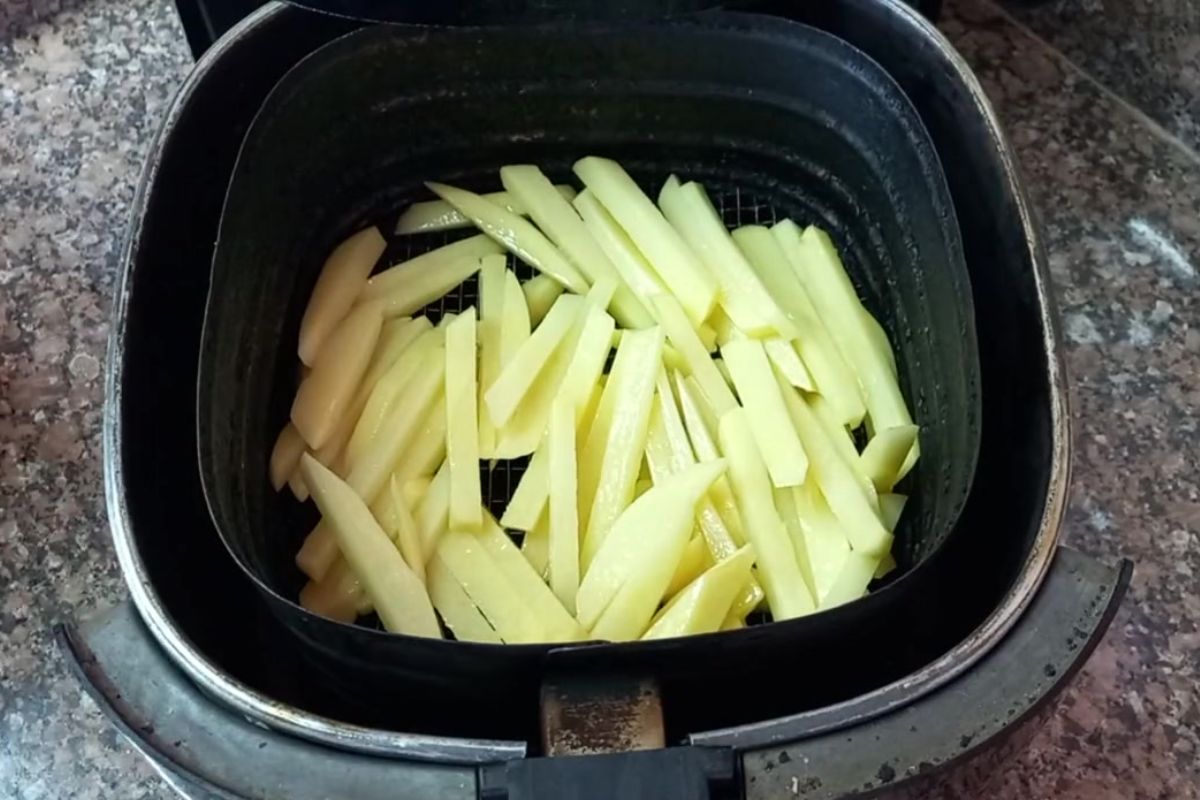 Batata inglesa cortada em palitos crua, disposta no cesto da airfryer antes do preparo