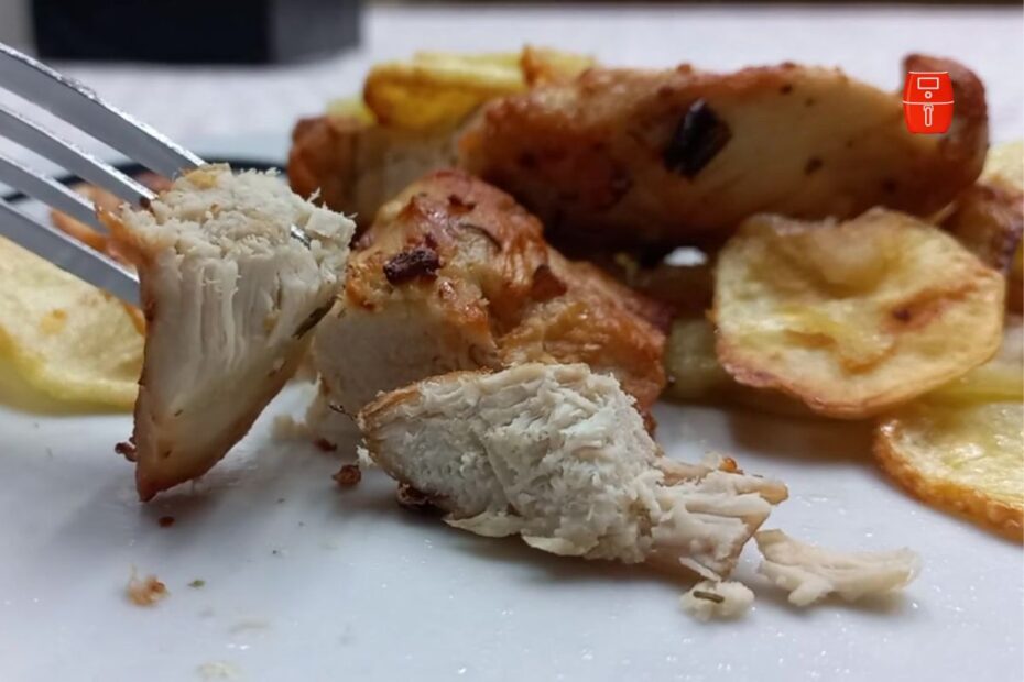 pedaços suculentos de peito de frango grelhados na air fryer, com interior macio à mostra, servidos com batatas chips douradas e crocantes ao fundo.