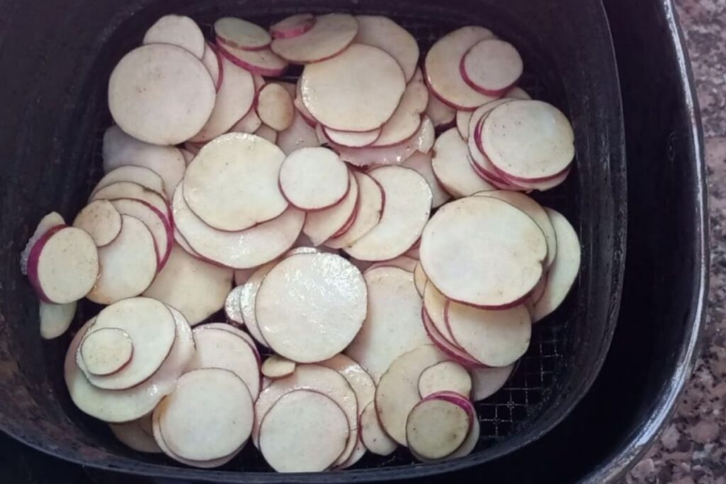 Fatias de batata doce organizadas sem sobrepor dentro do cesto da airfryer
